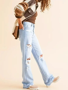 Détails d'un jean bleu clair à taille haute avec genoux déchirés et ourlets bruts