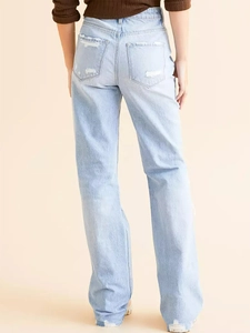 Détail du jean bleu clair montrant les poches arrière et l'ourlet en denim déchiré