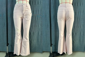 Detail of heart-shaped distressed cut-outs and raw hems on pink flared jeans