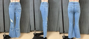Detail of light blue flare jeans with heart-shaped distressed cutouts and frayed hems