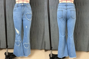 Detail of light blue flare jeans featuring heart-shaped distressed cutouts and raw hems