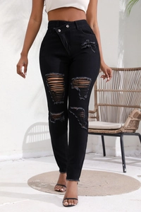 Détail du jean noir taille haute avec taille asymétrique et texture denim déchirée tendance