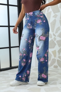 Dettaglio della stampa floreale rosa su jeans blu a vita alta e gamba larga