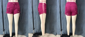 Detail of hot pink ripped denim shorts featuring lace-up sides and frayed raw hems