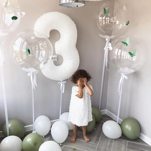Detailed view of white number 3 balloon and green latex set with girl in party dress