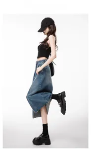 Detail showing high-waisted denim skirt with raw hem and split design on white background
