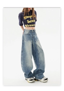 Detail of high-waist baggy jeans showing vertical seam stitching and washed blue denim texture