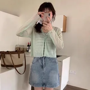Chic light green knit cardigan with tie-front design paired with denim mini skirt