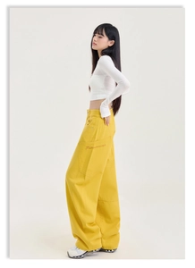 Détail du pantalon cargo jaune montrant la broderie de lettres sur la poche latérale