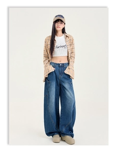 Détail d'un jean large à coutures incurvées avec broderie de lettres et surpiqûres contrastées