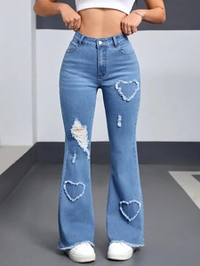 Detail of heart-shaped distressed cutouts and frayed hems on light blue flare jeans
