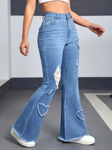 Detail of light blue flared jeans featuring heart-shaped distressed cutouts and frayed hems