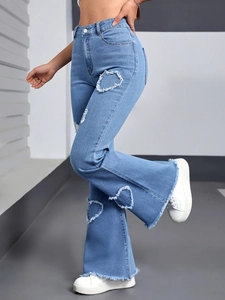 Detail of heart-shaped distressed cutout and frayed hem on light blue flared jeans