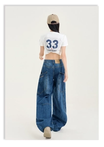 Détail du jean large avec patch en cuir et crop top blanc avec broderie bleue
