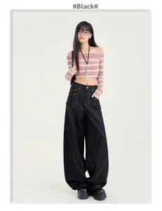 Détail du pantalon en jean foncé ample avec coutures orange contrastées et poches