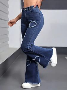 Detail of high waisted flare jeans featuring heart-shaped frayed cutouts and raw hems