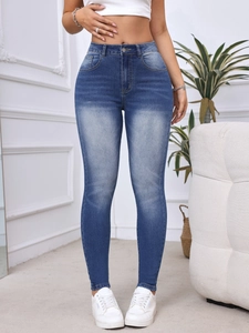 Dettaglio dei jeans blu slim a vita alta con lavaggio vintage e trame a baffi