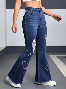Detail of high waisted flare jeans featuring heart-shaped distressed cutouts and raw hems