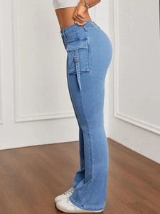 Dettaglio dei jeans a zampa a vita alta con tasche cargo laterali e fibbie decorative