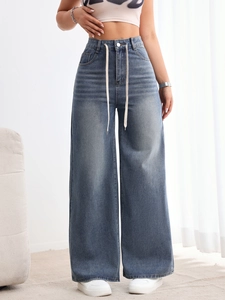 Détail d'un jean large à taille haute, coloris bleu délavé rétro avec cordon de serrage réglable