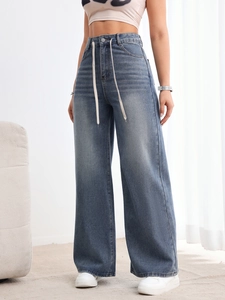Détail d'un jean large taille haute avec cordon blanc et finition délavée vintage