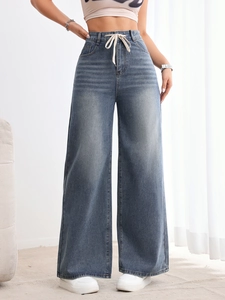 Détail d'un jean taille haute à jambe large avec cordon de serrage et denim bleu délavé