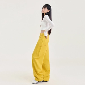 Femme en crop top blanc et pantalon cargo jaune large avec broderie élégante