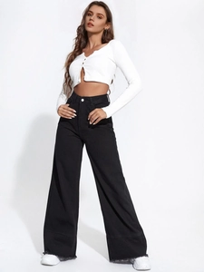 Close-up of high waist black wide leg jeans featuring raw frayed hem and denim texture