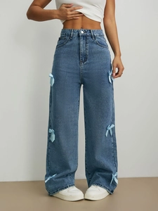 Détail du jean large taille haute bleu clair avec nœuds en satin sur les côtés