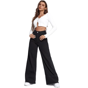 Close-up of high waist wide leg black denim jeans with raw hem and white platform sneakers