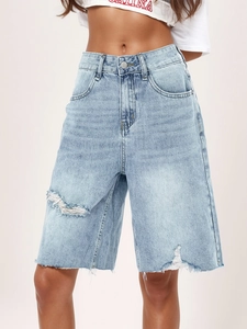 Detail showing high-waist denim shorts with distressed ripped holes and raw hem edges