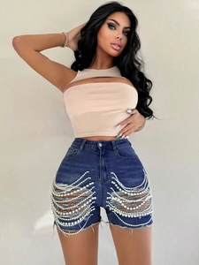 Détail de short en jean taille haute bleu avec déchirures et chaînes de perles chic