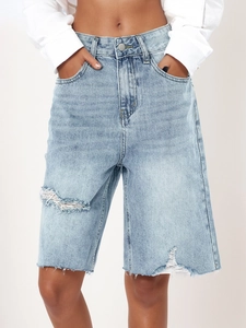 Detail of high waisted light blue denim shorts with ripped fraying and distressed hem