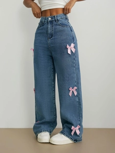 Gros plan sur un jean droit à taille haute avec nœuds décoratifs en satin rose sur les côtés