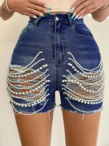 Détail du short en jean taille haute avec découpes déchirées et chaîne de perles élégante