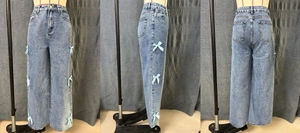 Détail d'un jean vintage taille haute à jambes larges avec nœuds en ruban bleu sur les côtés