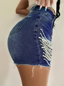Détail du short en jean taille haute avec découpes latérales et broderies de perles blanches