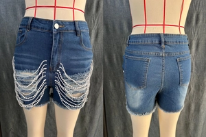 Détail de short en jean taille haute avec déchirures et chaînes de perles blanches décoratives