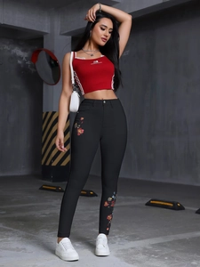 Gros plan sur un jean skinny à taille haute brodé et un haut court rouge sans manches