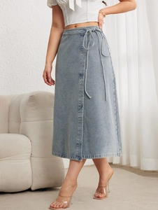 Détail d'une jupe midi en jean bleu clair délavé avec lien à la taille et fente latérale