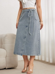 Détail d'une jupe mi-longue en jean bleu clair avec cordon de serrage et fente
