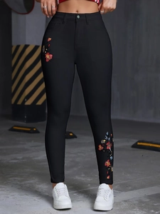 Gros plan sur un jean skinny noir taille haute avec broderies florales colorées