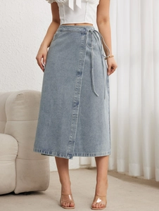 Détail d'une jupe portefeuille en jean bleu clair avec lien à la taille et fente élégante