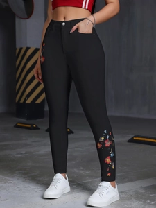 Détail de la broderie florale colorée sur un jean skinny noir extensible à taille haute