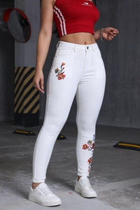 Détail de la broderie florale colorée sur un jean skinny blanc extensible taille haute