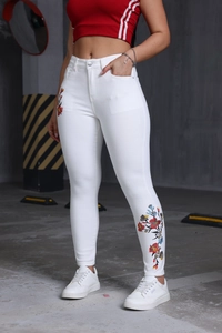 Détail de la broderie florale colorée sur le jean slim blanc à taille haute pour femme