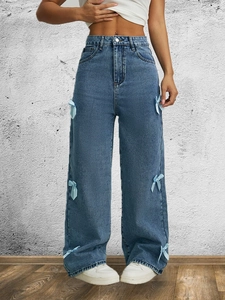 Dettaglio di jeans a gamba larga a vita alta azzurri con decorazioni a fiocco laterali