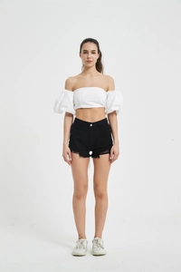 Front view of black distressed denim shorts with frayed hems and a white off-shoulder top
