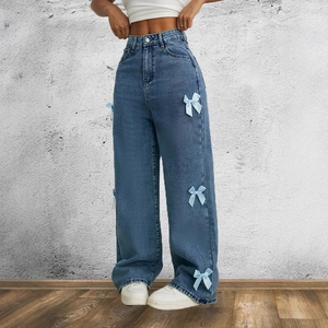 Dettaglio dei jeans blu a vita alta con fiocchi di raso azzurro lungo le gambe
