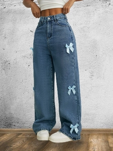 Dettaglio dei jeans in denim a gamba larga a vita alta con fiocchi decorativi in seta